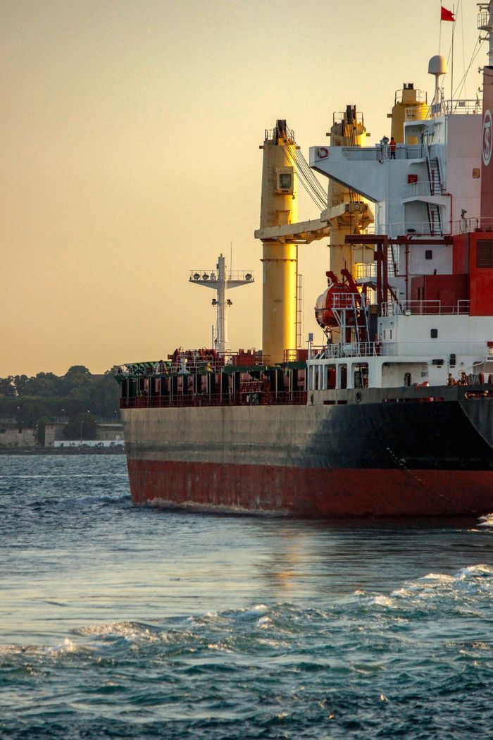 A cargo ship sails through İstanbul during sunset, showcasing maritime transportation.