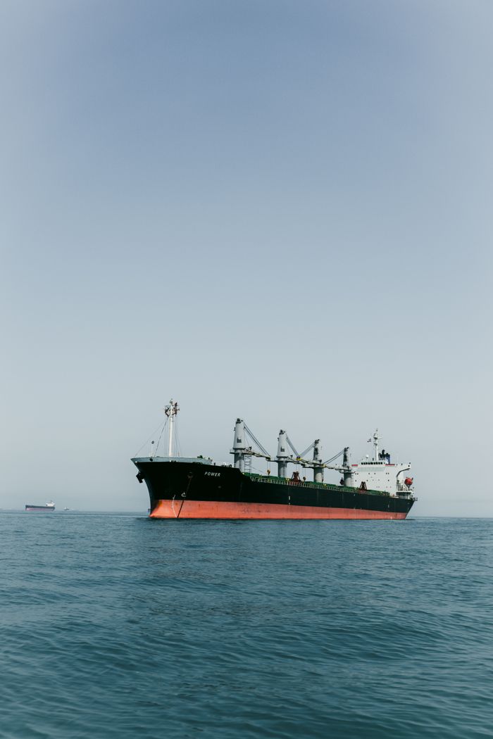 A large cargo ship navigates the tranquil waters of the open sea on a clear day.