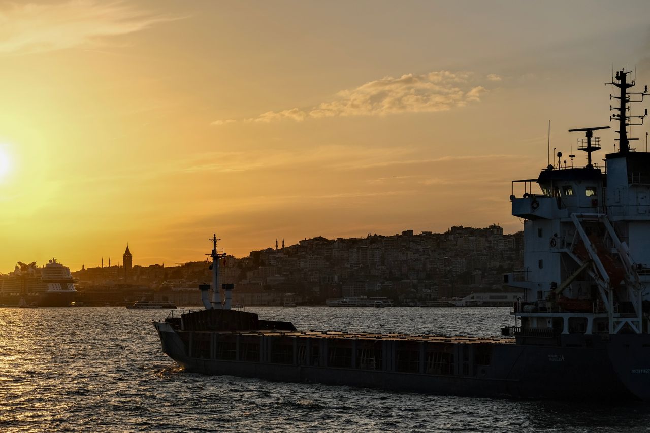 Stunning sunset over İstanbul with a cargo ship and silhouette of Galata Tower on the Bosporus.